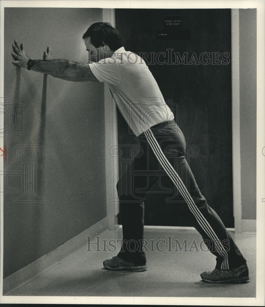 1989 Press Photo Costello Stretches His Leg Muscles Before Going For A Run - Historic Images