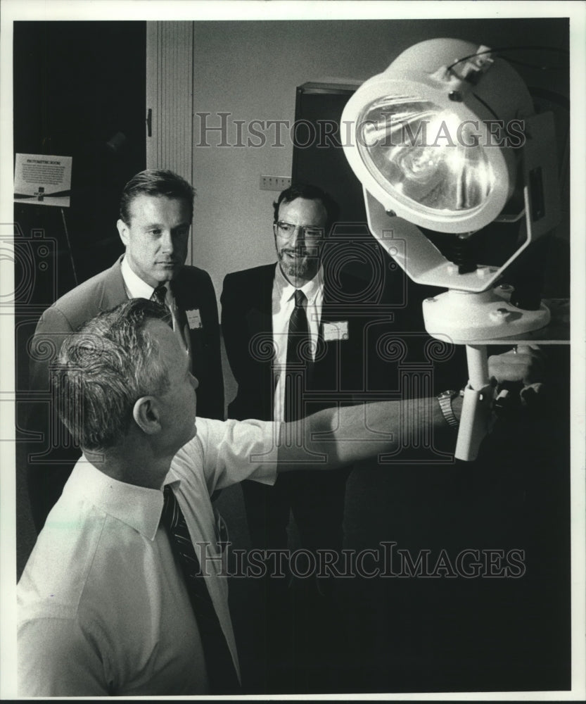 1989 Press Photo Members of Phoenix Products, inc displays a marine searchlight - Historic Images