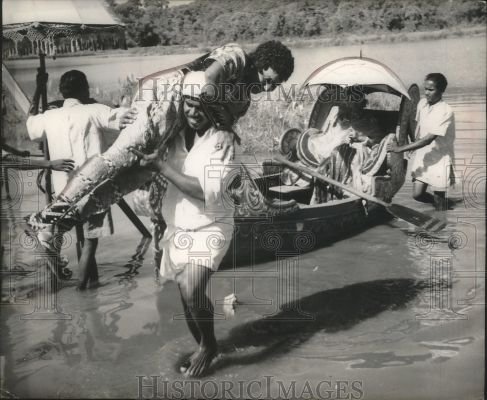 1952 Press Photo Movie Industry Assistant carries actor out of boat India - Historic Images