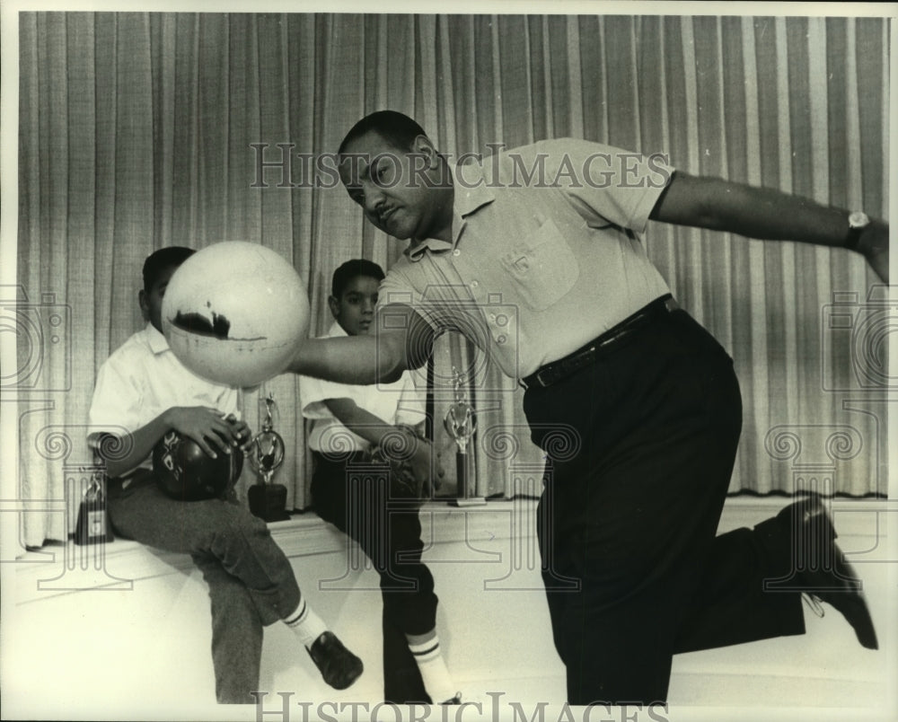 1963 Press Photo Carl Rowan shows sons, Carl &amp; Geoffrey, his bowling technique - Historic Images