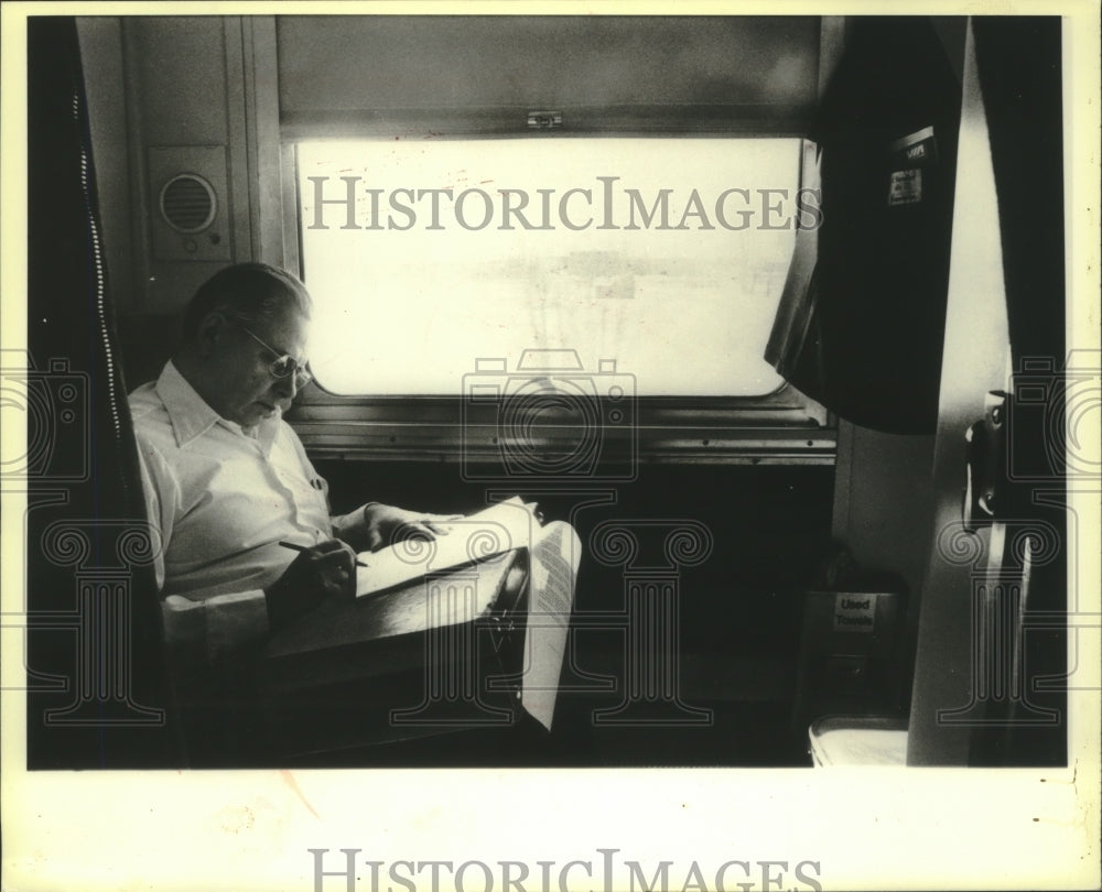 1980 Press Photo National Railway Passenger Service guest does paperwork in room - Historic Images
