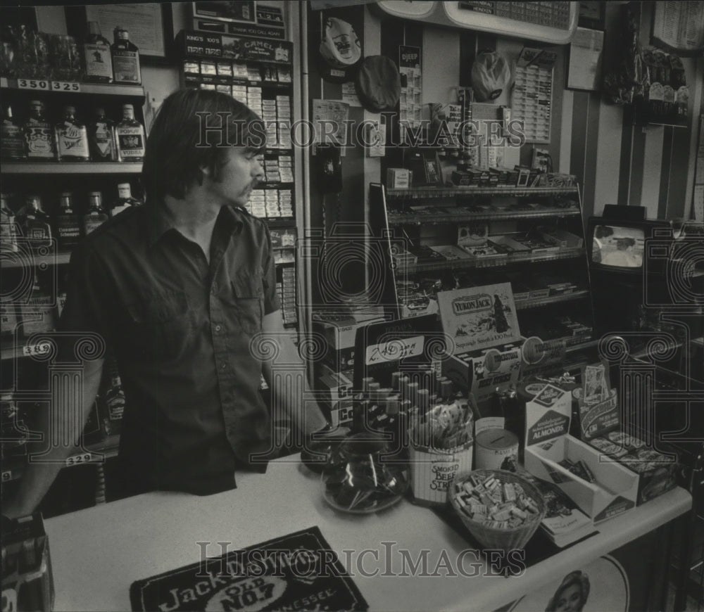 1985 Press Photo Roland Burns at liquor store watching TV news, Wisconsin. - Historic Images