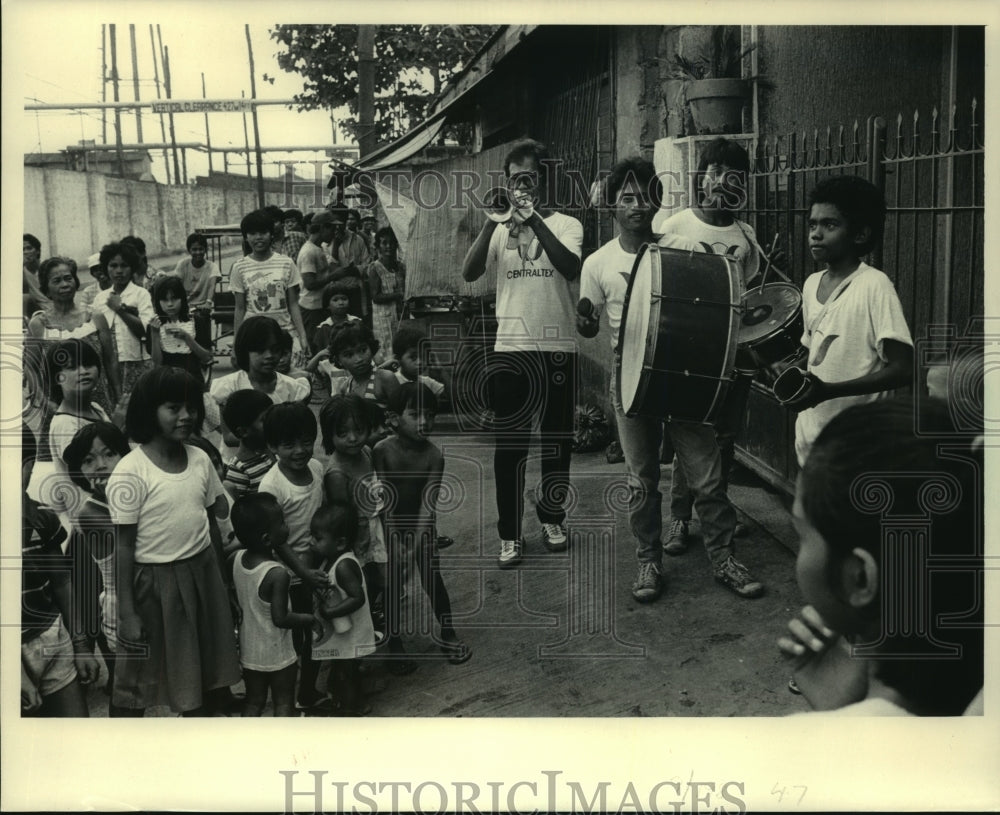 1986 A street band playing for kids among homes in the Philippines. - Historic Images