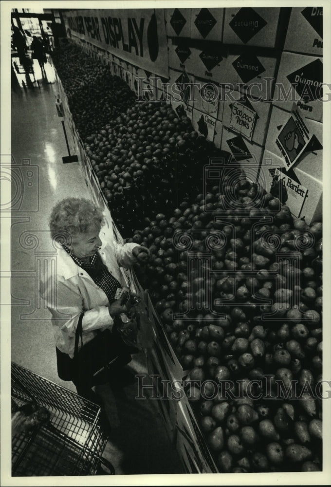 1990 Press Photo Miriam Holmes picks pears at Pick &#39;N Save&#39;s huge fruit display - Historic Images