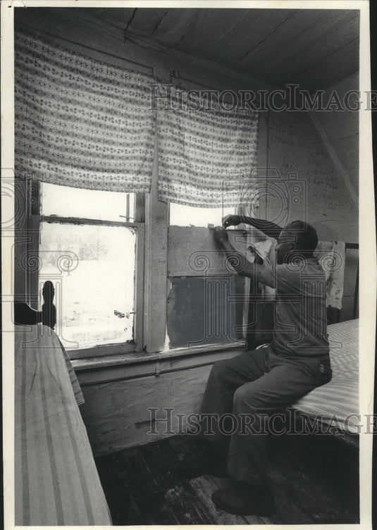 1971 Press Photo Lewis Limmit tapes cardboard to broken window in Milwaukee slum - Historic Images