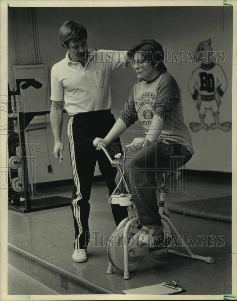 1985 Instructor Barry McLaughlin takes Denise Steger&#39;s pulse on bike - Historic Images