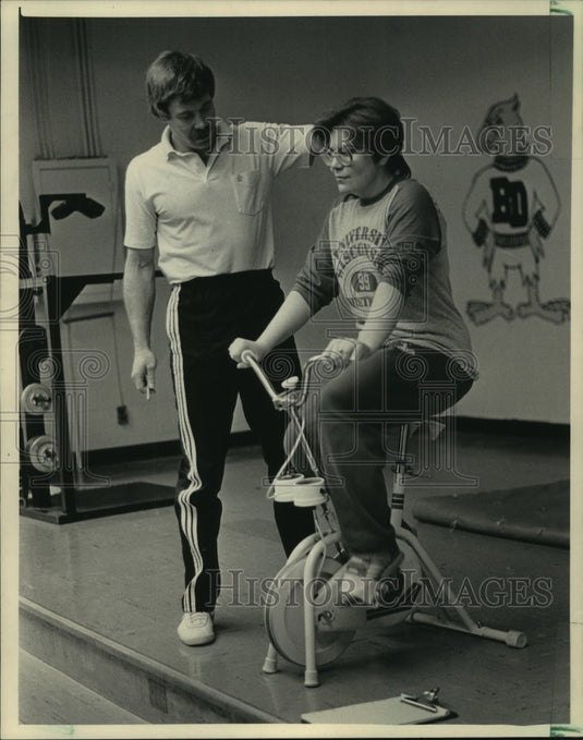 1985 Instructor Barry McLaughlin takes Denise Steger's pulse on bike - Historic Images