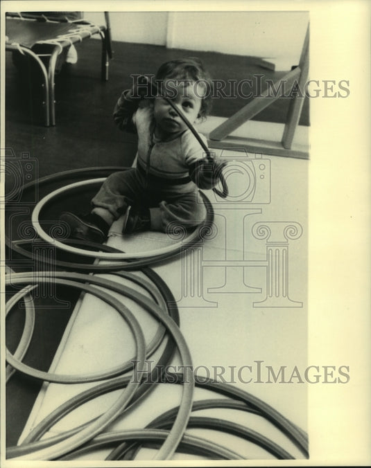 1986 Press Photo Child plays on floor with hoops - mjb86558 - Historic Images