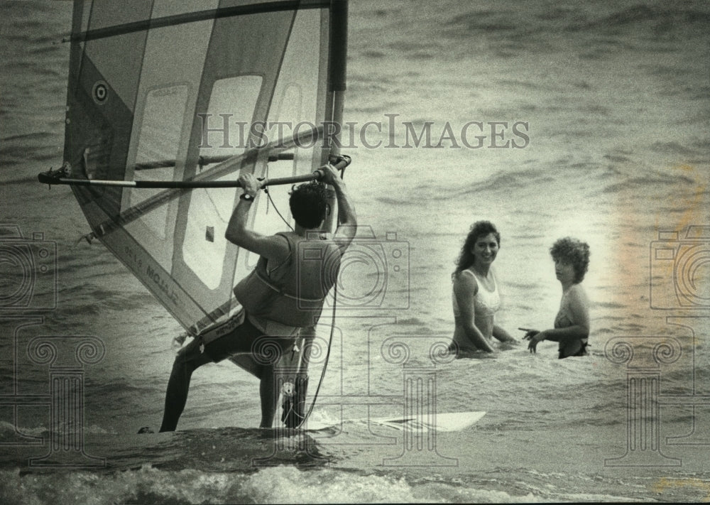 1989 Press Photo Lake Michigan windsurfer glides past swimmers at Bradford Beach - Historic Images