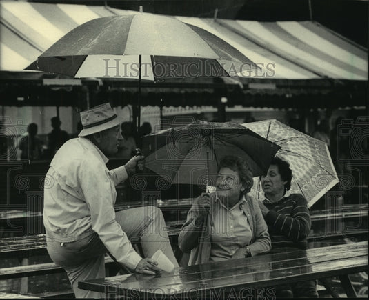 1985 Visitors to Polish Fest use umbrellas to stay dry. - Historic Images