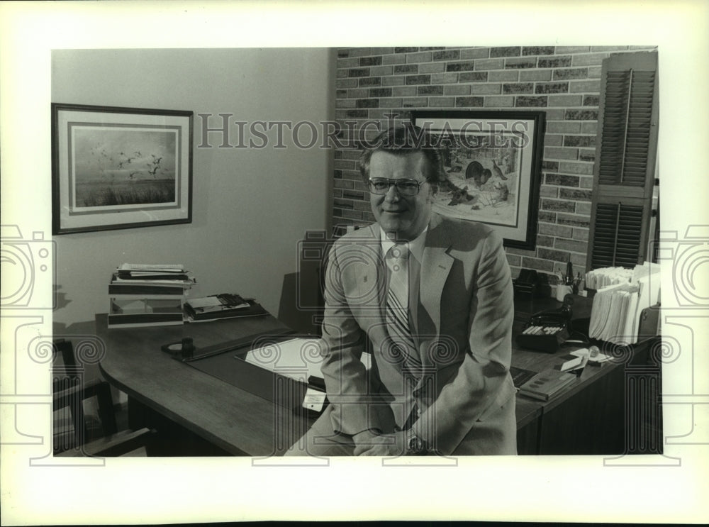 1982 Press Photo Charles Rushman, President Merrill Lynch Realty, sits on desk - Historic Images