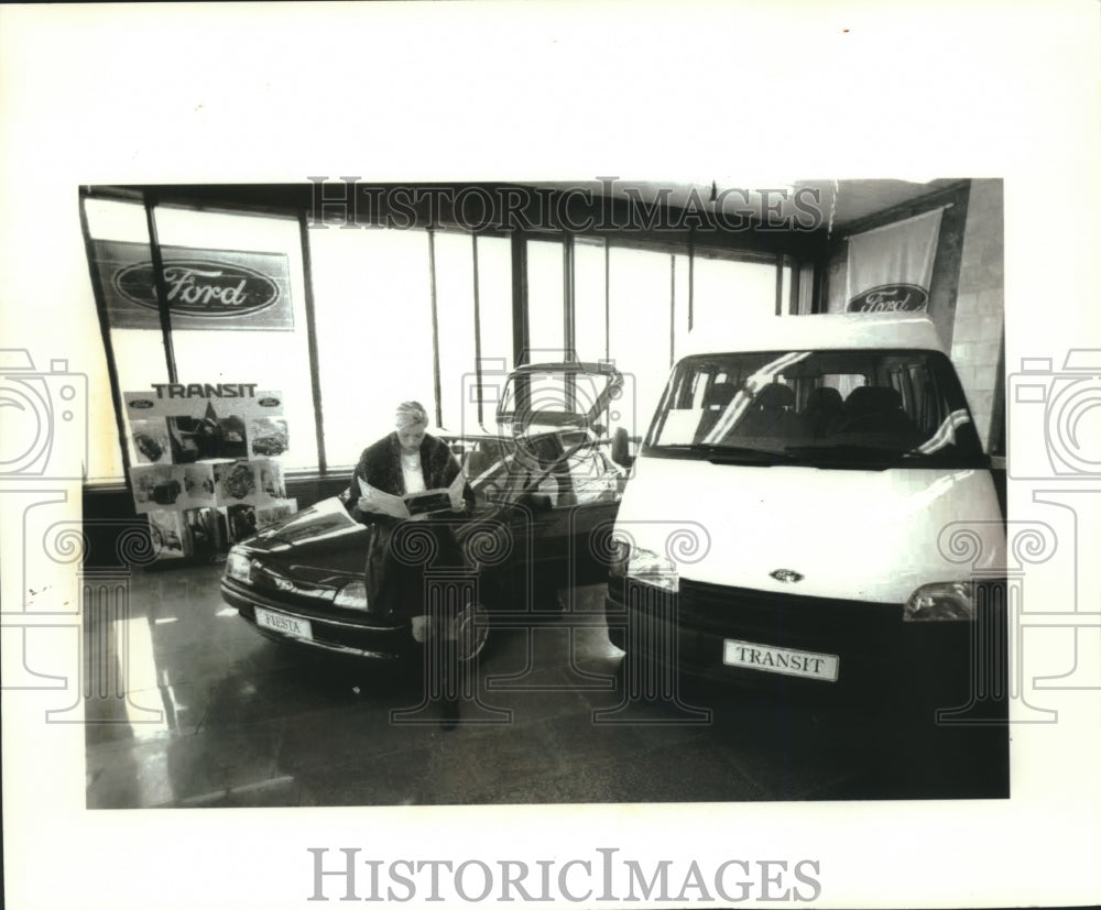 1992 Press Photo Women sits on car, reads Ford Fiesta brochure, St. Petersburg - Historic Images