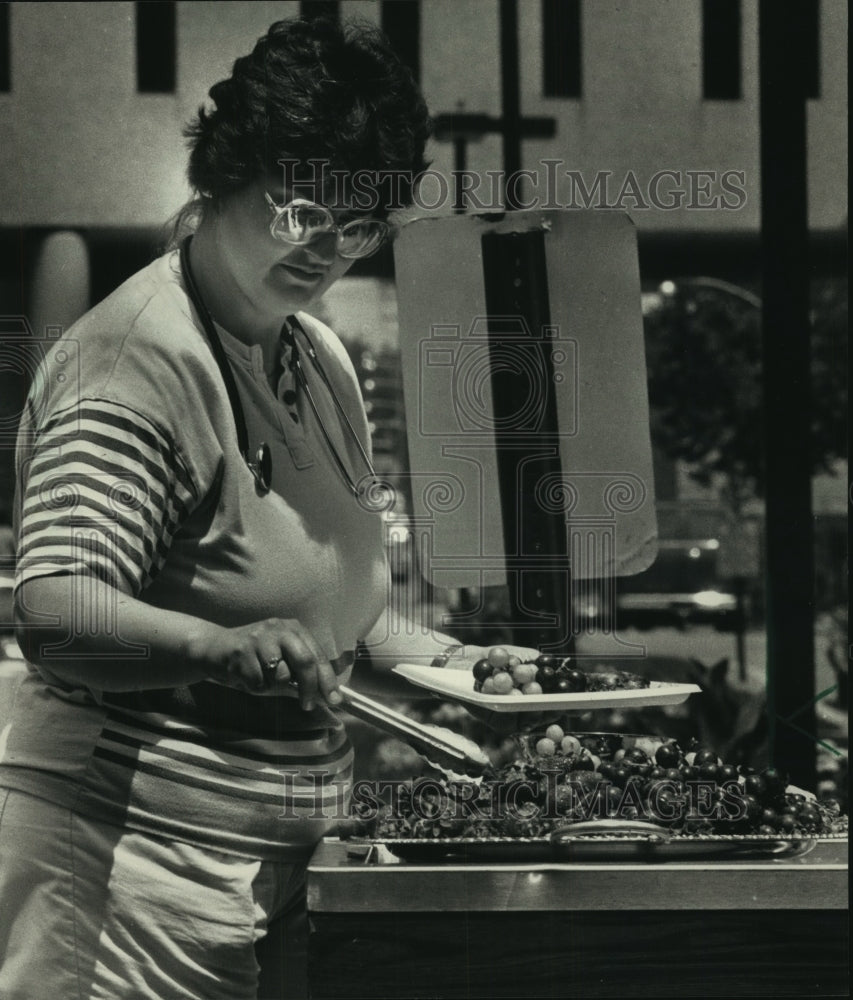 1988 Press Photo Terri Pawlak nurse picking fruit outside Saint Luke&#39;s Hospital. - Historic Images