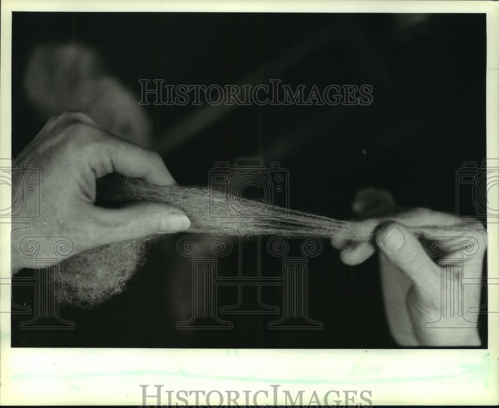 1983 Press Photo Spinning wool strands as they are fed into the spinning wheel - Historic Images