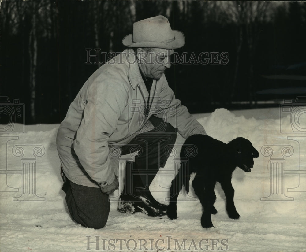 1964 Press Photo Pat Wilsie helps three day old Karakul lamb walk in snow.-Historic Images