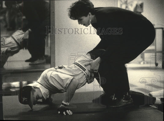 1992 Aaron Powless does push-ups as therapist helps him through task-Historic Images