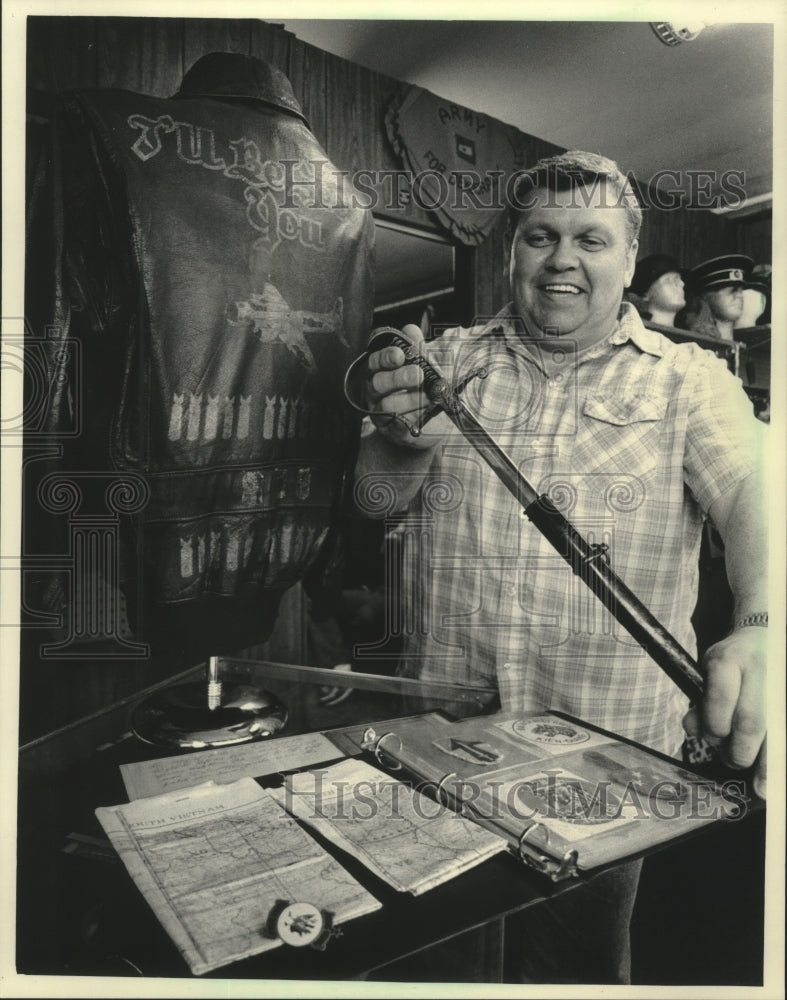 1986 Press Photo William Scott drawing a sword at his Military store, Milwaukee. - Historic Images