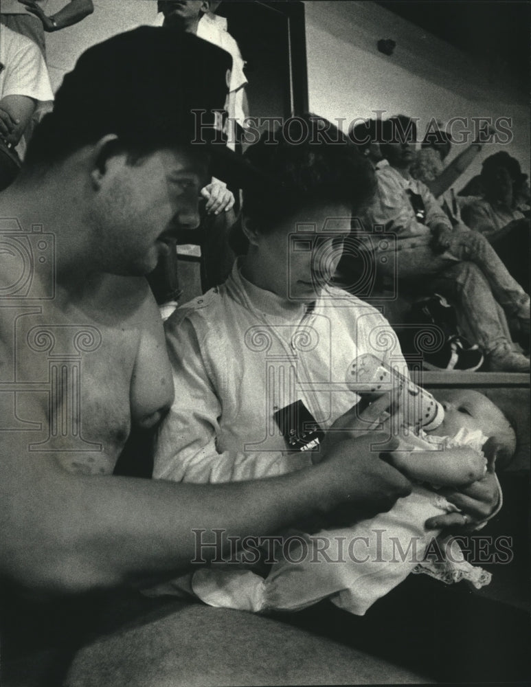 1991 Press Photo Milwaukee handicapped swimmer, Lyle Sukkert helps feed his baby - Historic Images