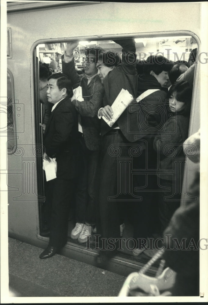 1986 Commuters squeeze into train at Tokyo's Shinjuku station - Historic Images