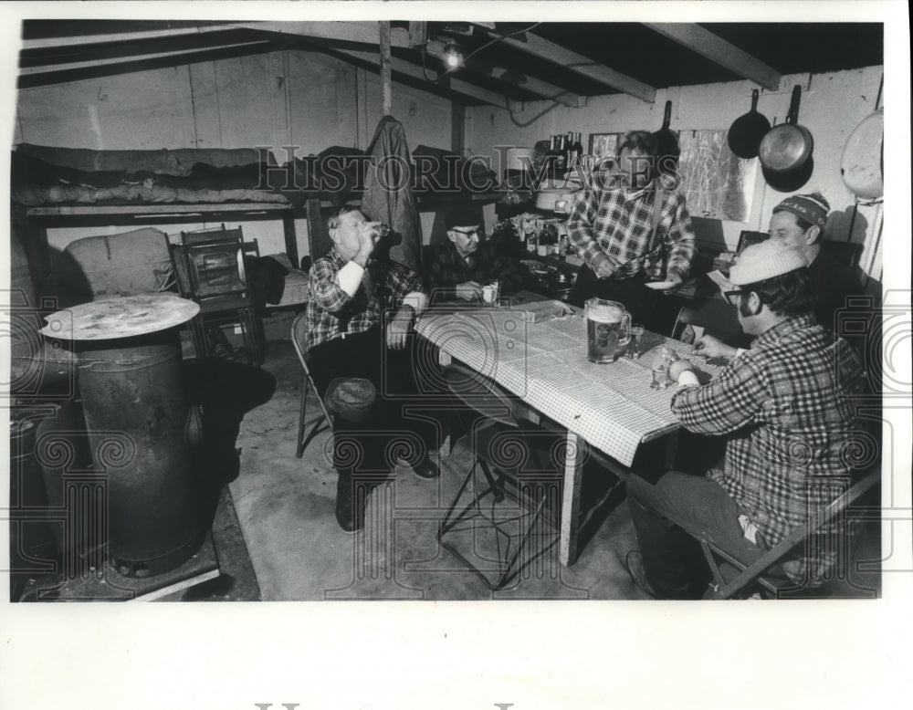 1978 Press Photo Deer hunters in cabin with oil space heater, gas stove and beds - Historic Images