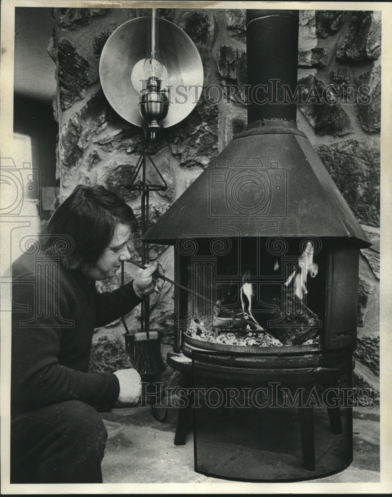 1977 Press Photo Jerry Zedler starting a fire in a wood burning stove in store. - Historic Images