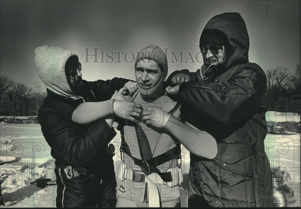 1985 Press Photo Man gets help with dive gear for under-ice rescue training. - Historic Images