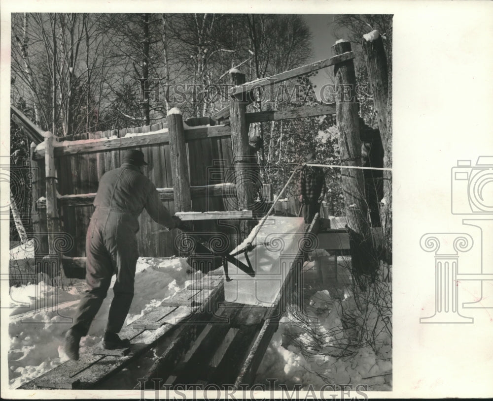 Press Photo Leroy Norlin guided a finished block of ice into the ice house. - Historic Images