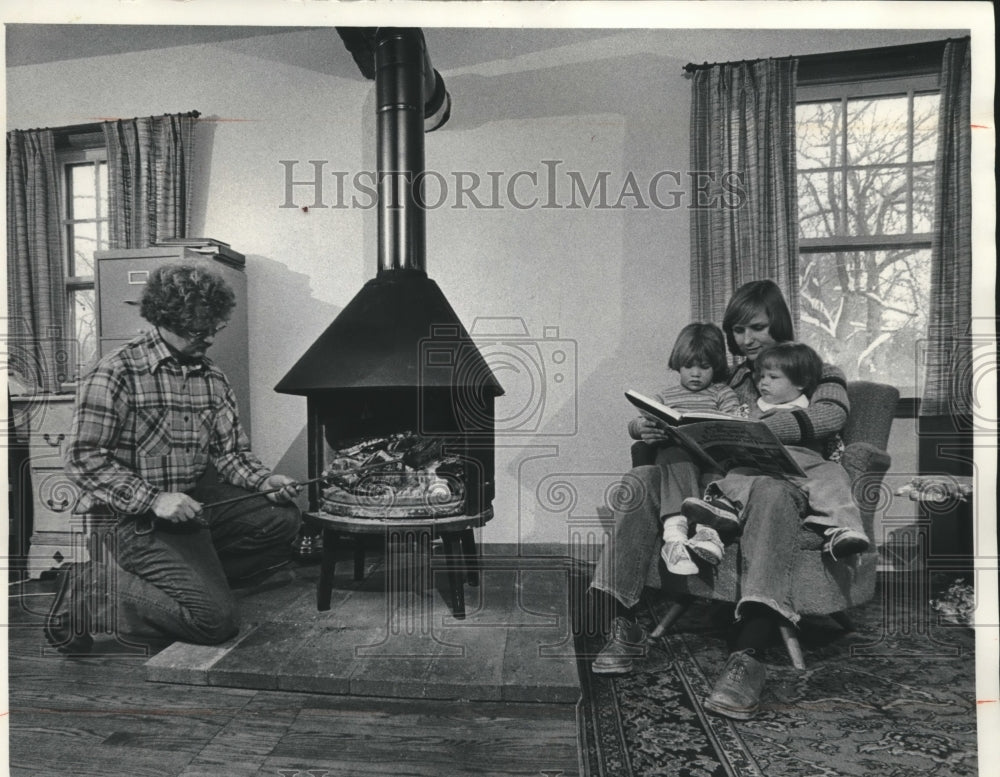 1978 Kathleen Eder reads to Rebecca next to wood burning stove - Historic Images