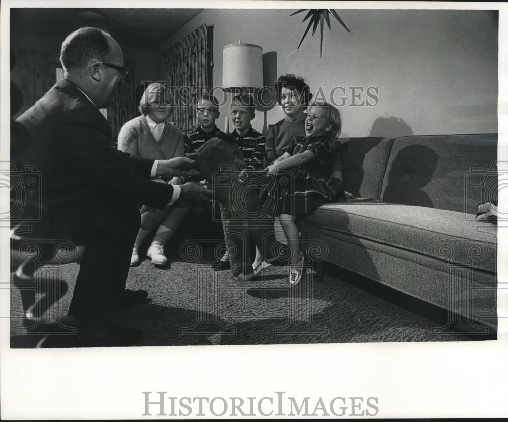 Press Photo Family watches Lynn E. Stalbaum hands teddy bear, to daughter Lori - Historic Images