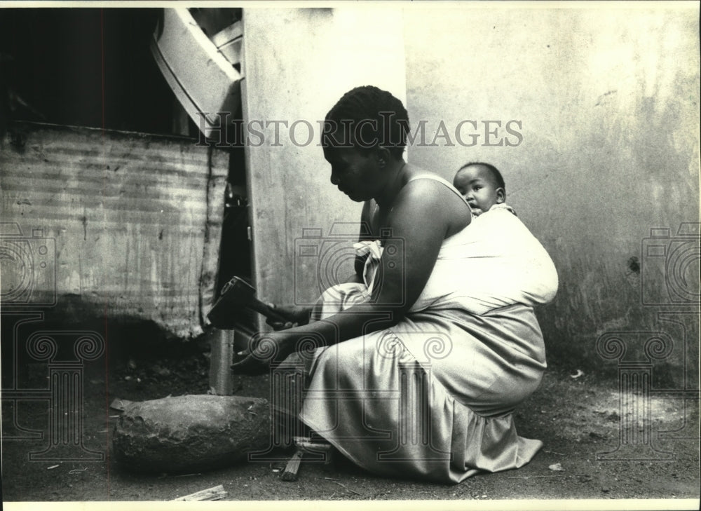 1990 Press Photo A Soweto mother chops wood , South Africa - mjc01211 - Historic Images