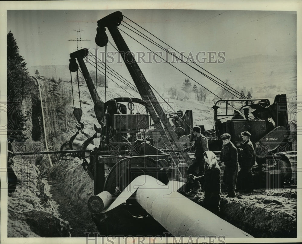 1962 Press Photo Men use crane to lower oil pipe into ground, Russia - mjc01528 - Historic Images