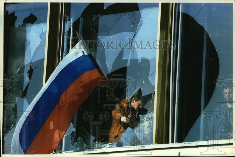 1993 Man flies Russian flag from broken window, Parliament, Moscow - Historic Images