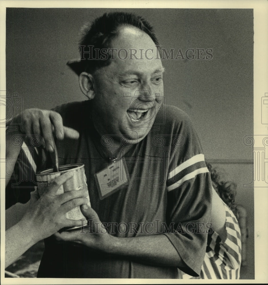 1987, John Kolodzinksi cracks up over sticky varnish can. - mjc02508 - Historic Images