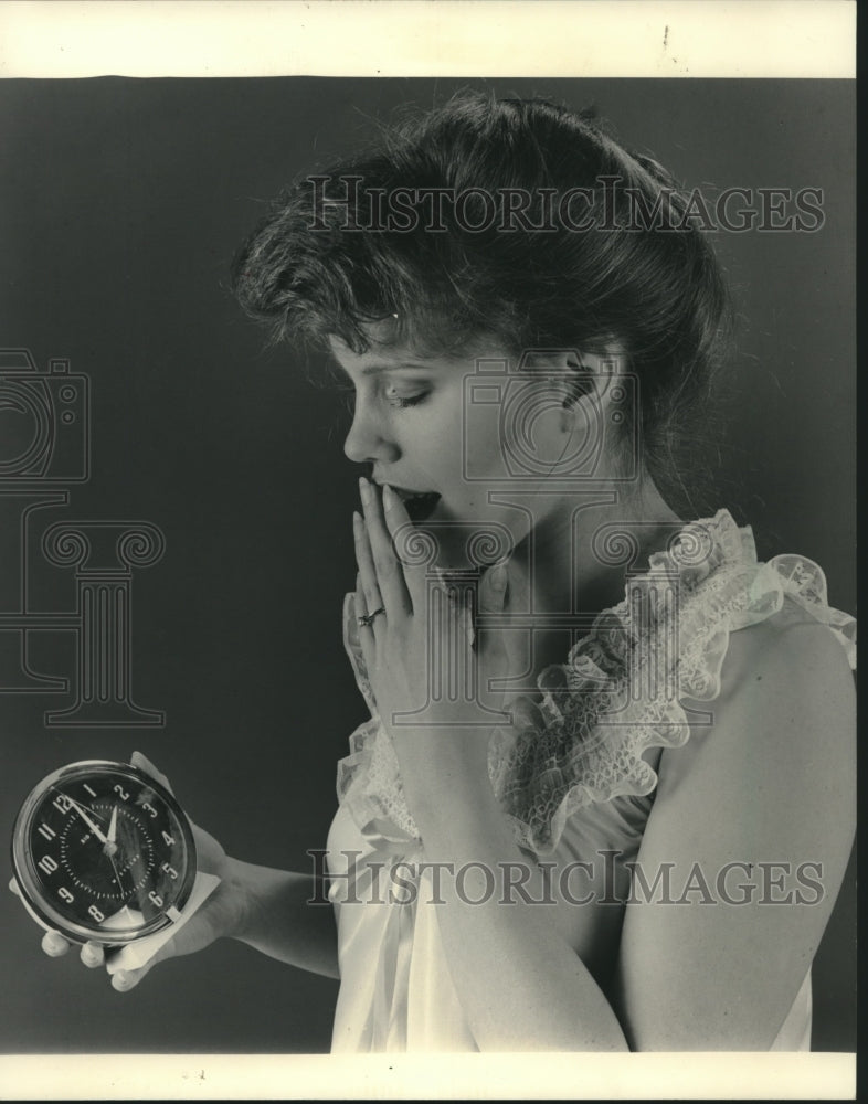 1983, Woman in nightgown yawns while holding alarm clock - mjc04631 - Historic Images