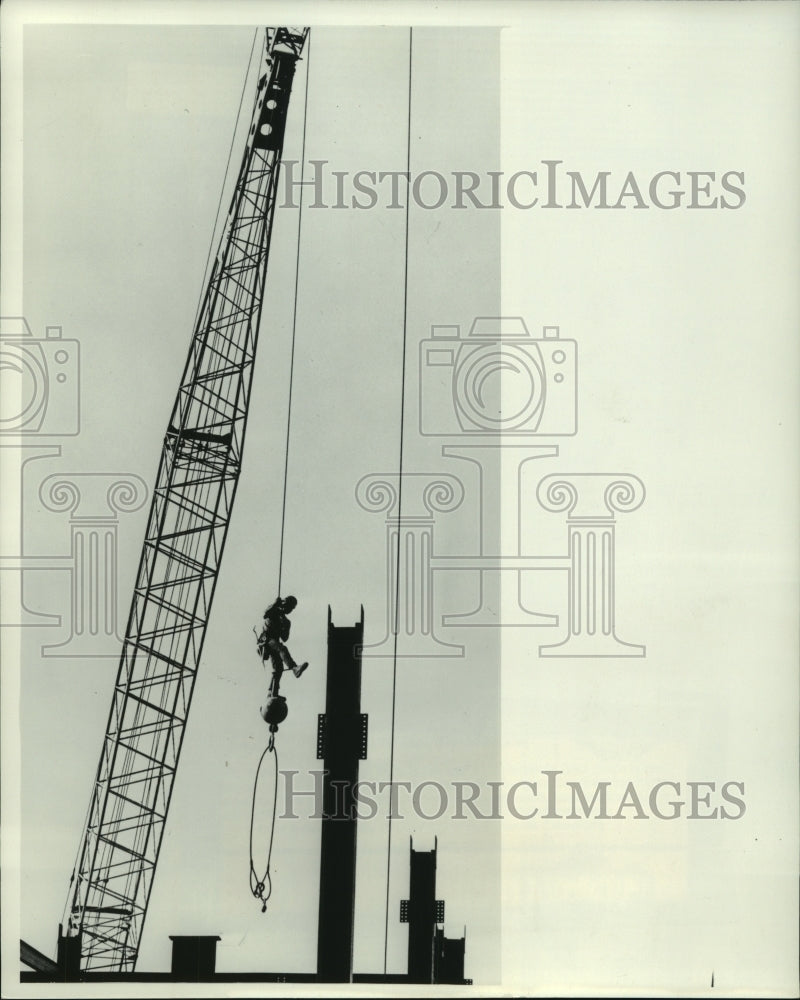 1977, Steeplejack Bob Menghe rides a steel ball up to work - Historic Images