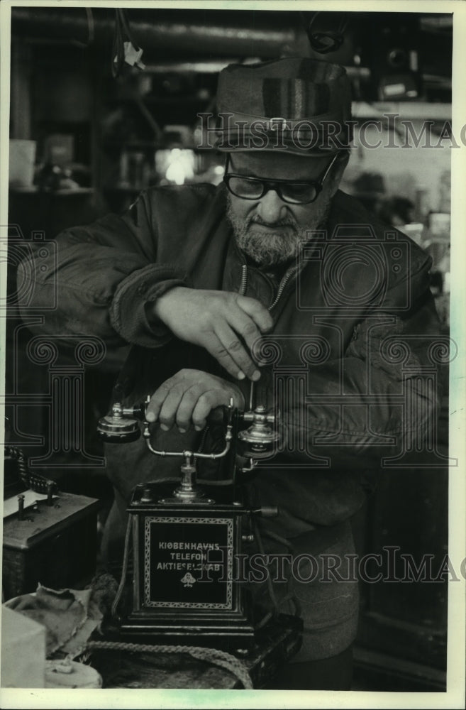 1983, Rudie Patmagria repairing a antique Greek phone Wisconsin - Historic Images