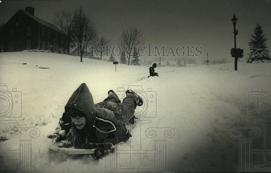 1987 Press Photo Jackie, Eric Odachowski, sleds down hill Brookfield, Wisconsin - Historic Images