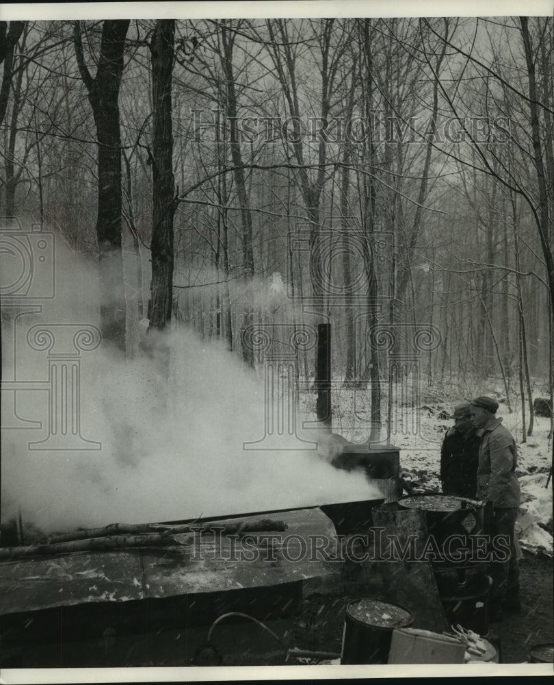 1957, Men stoke fire in cooker to boil sap down to Maple sirup - Historic Images