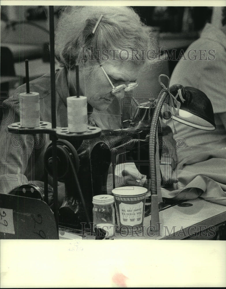 1983, Sewing Machine operator sews garment pieces together - Historic Images