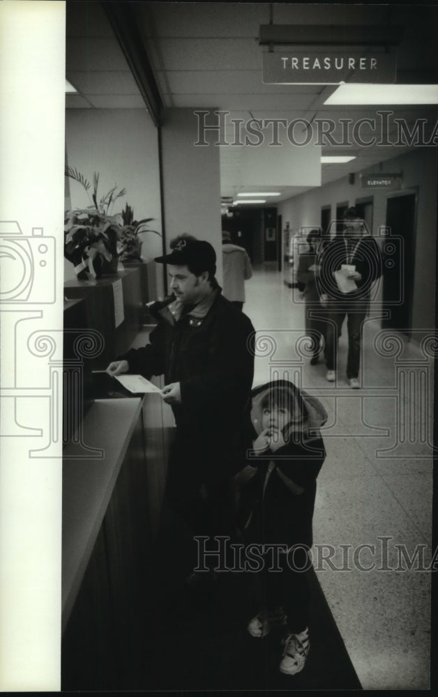 1994 Press Photo MIgiel Jestrada,4, waits while his father, Jose, pays taxes - Historic Images