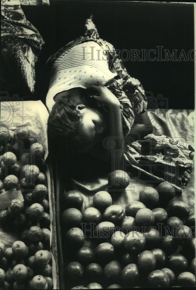 1988 Press Photo Woman Naps On Her Wares At Abidjan Marketplace On Ivory Coast - Historic Images