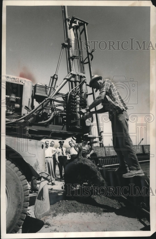1961, Workmen use post hole digger on leaky pipe line on Jones island - Historic Images