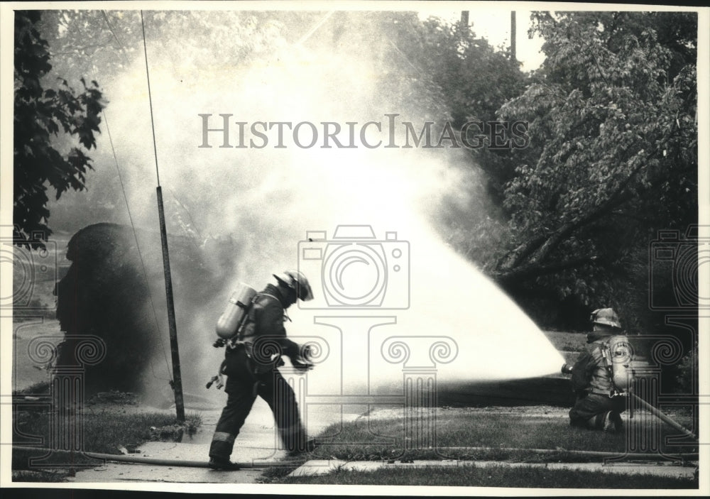 1991 Firefighters spray water on broken gas line after storm, WI-Historic Images