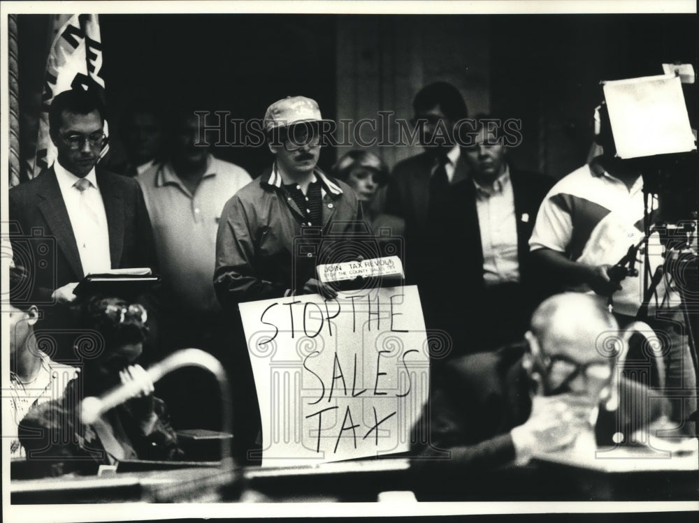 1990 Press Photo Jim Soderno holds a sign opposing Milwaukee county sales tax - Historic Images