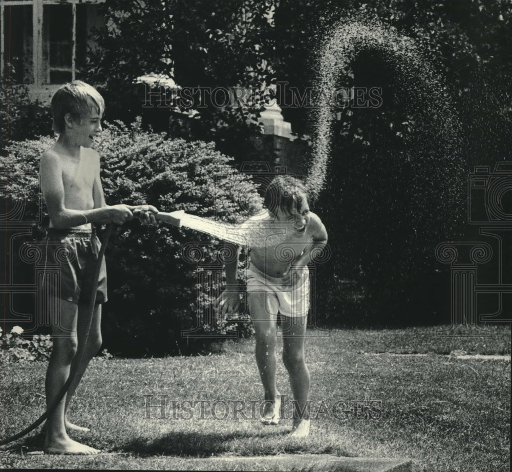 1985, Martin Lemke sprays Nathan Gruenwald with hose, Milwaukee - Historic Images