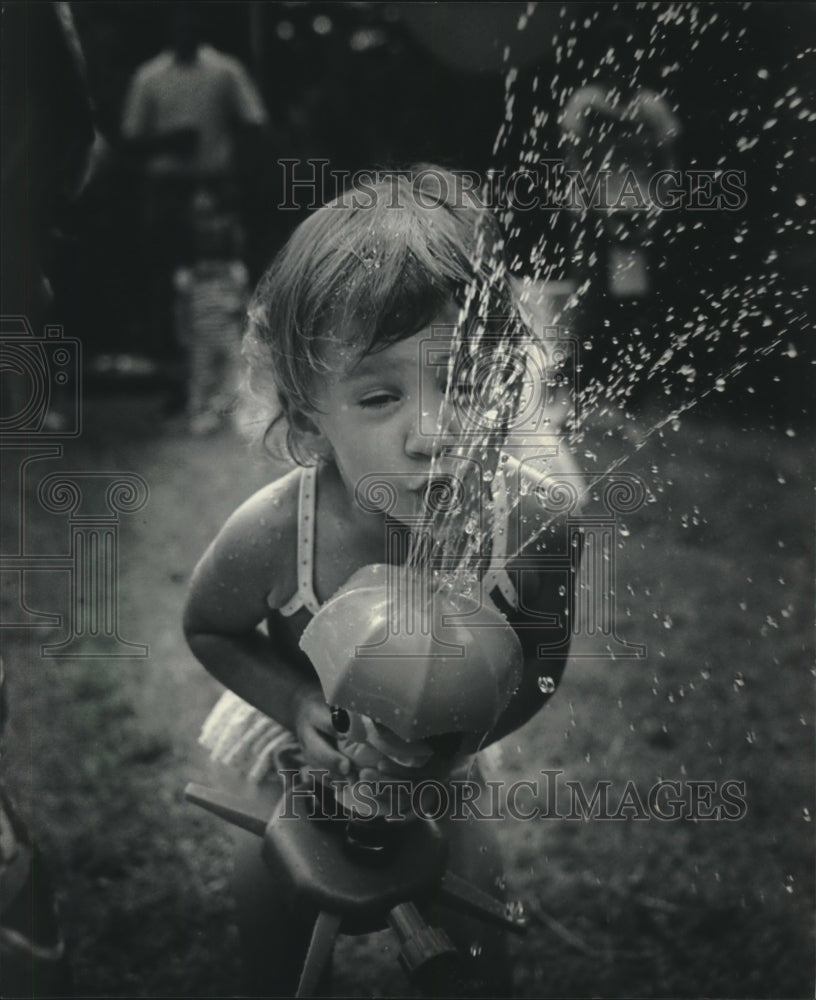 1985, Cristina Springbob relieves summer heat via a water sprinkle - Historic Images