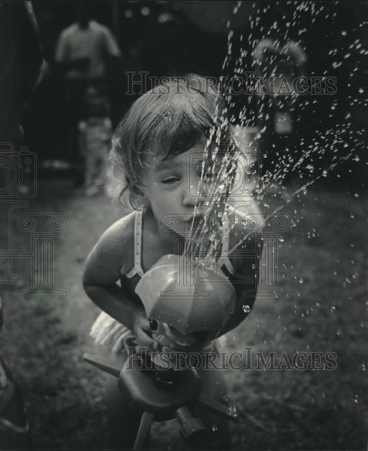 1985, Cristina Springbob relieves summer heat via a water sprinkle - Historic Images