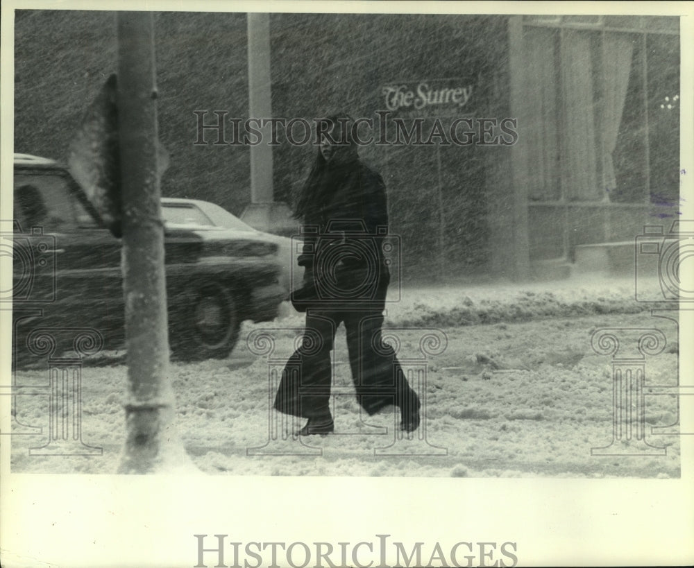 1965 Press Photo Girl walking through wet and blowing snow Milwaukee, Wisconsin - Historic Images