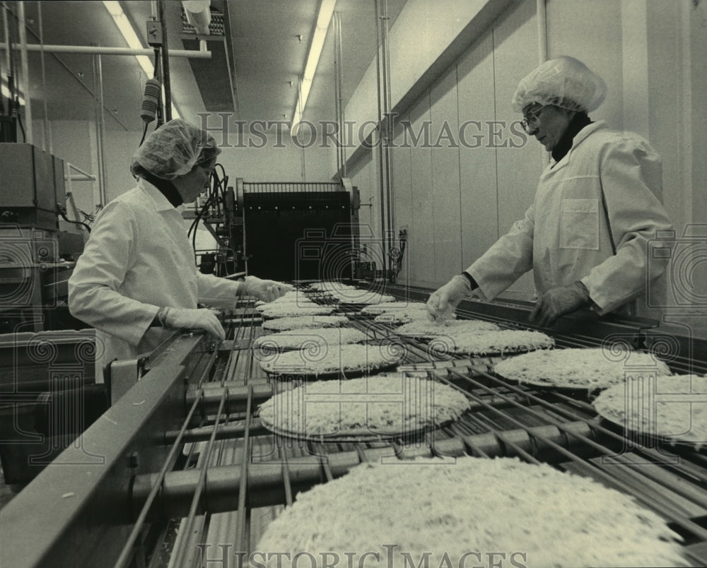 1983, Workers check pizzas at the Tombstone Pizza Corp. assembly line - Historic Images