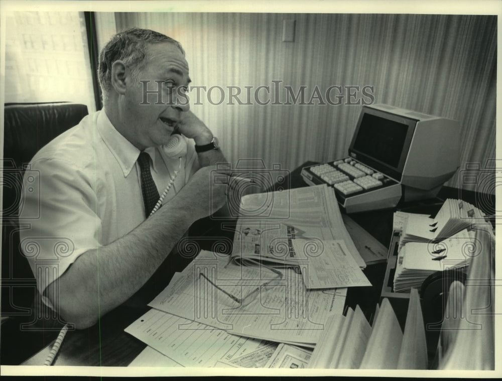 1984, Joe Danton takes call in office Robert Thomas Securities Inc - Historic Images